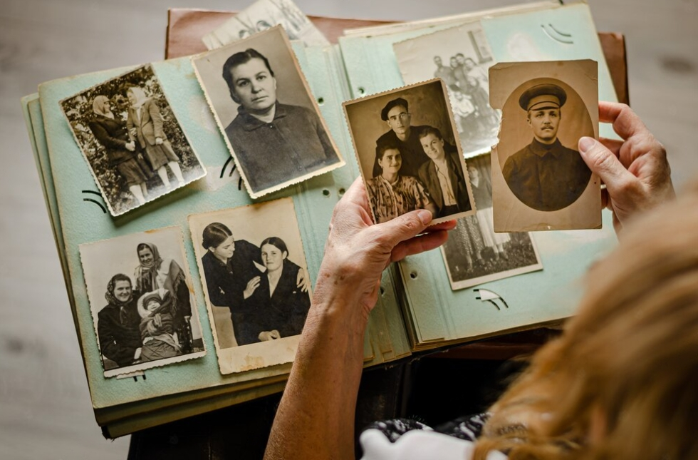 woman’s hands holding old photo and album of ancestors