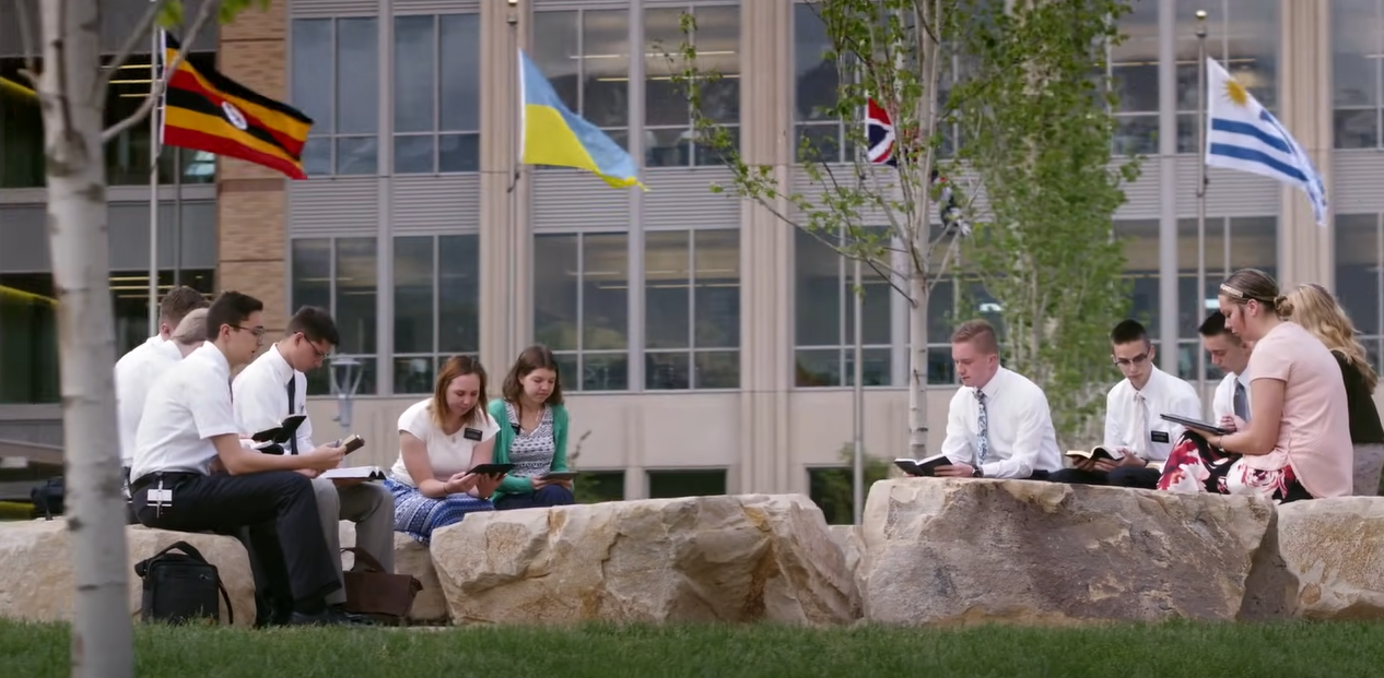 people outdoors, seated on large rocks reading books