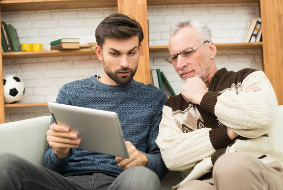 two men sitting on a coach and watching on a tablet