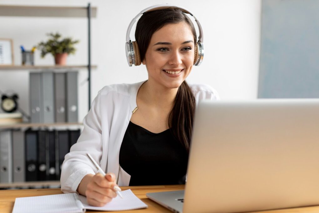 A woman sits at her computer and takes notes