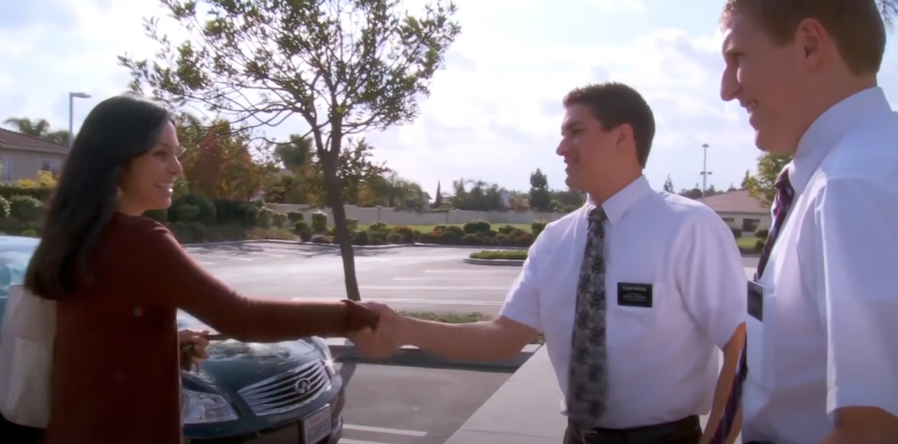 Two men in formal attire shaking hands with a female